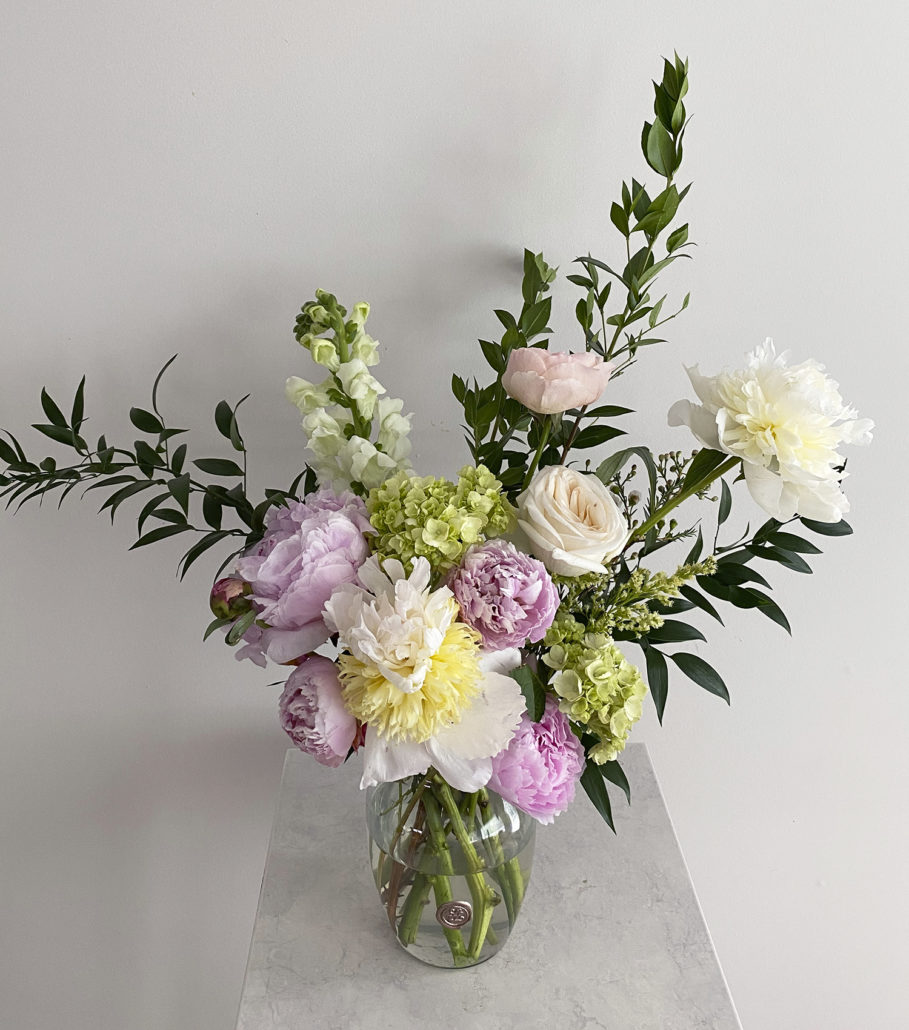 Gorgeous fresh floral arrangement in clear glass vase on marble table